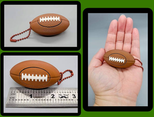 Football keychain ball clicker toy shown in hand and measured with ruler for scale
