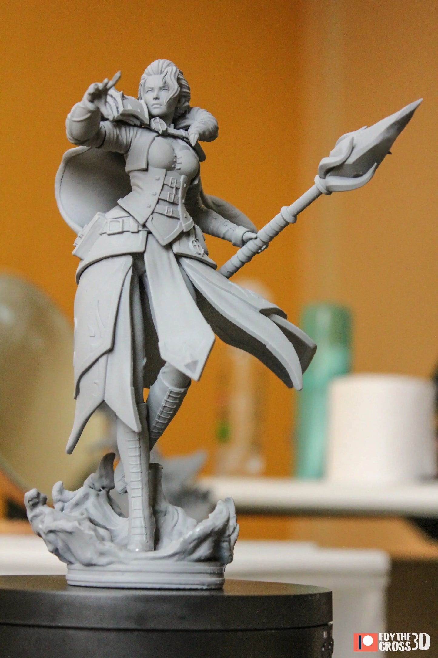 Unfinished sculpture of a warrior holding a spear on a black base against an orange background