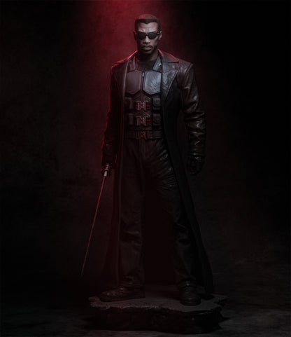 Statue of a character in a dark outfit with a red light, set against a dark background