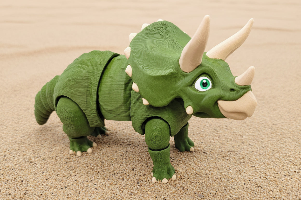 Toy triceratops dinosaur on a sandy background