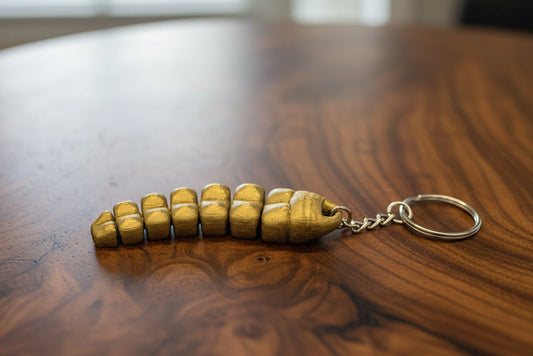 Bronze-colored keychain shaped like a rattlesnake tail on a wooden surface