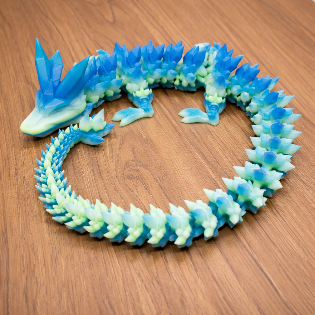 Articulated crystal dragon toy with translucent blue and green segments posed in a circular shape on a wooden surface