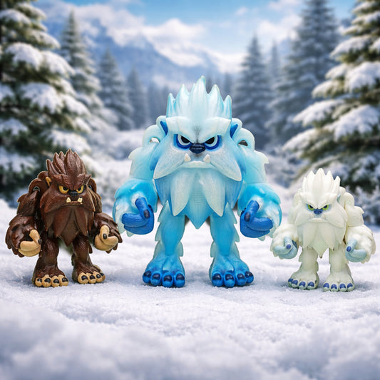 Articulated posable yeti and bigfoot fidget toys displayed together on a snowy winter style background. The bigfoot figure is shown in deep brown with tan accents and dark facial details. The large yeti is icy blue with frosted light blue highlights and darker blue hands and feet. The smaller yeti is white with pale icy blue accents and soft pastel details. All figures feature expressive faces, textured fur, and movable joints. Available as a toy or keychain with fully customizable color options.