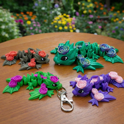 Articulated baby rose wyvern toy and keychain with colorful rose details displayed on a wooden table outdoors.