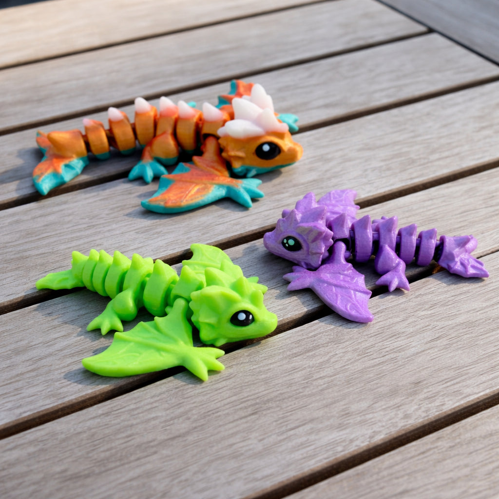Articulated baby wyvern toy in bright green purple and orange colors displayed on a wooden surface, fantasy dragon keychain size collectible