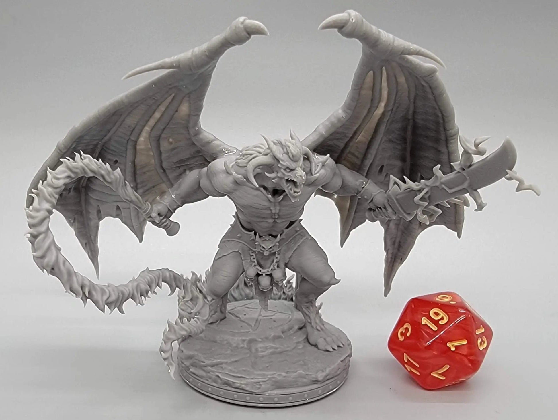 Resin-printed Balor Vogron demon miniature with wings, swords, and flame tail next to D20 die – 32mm or 75mm scale boss for DnD, Pathfinder, and TTRPG display