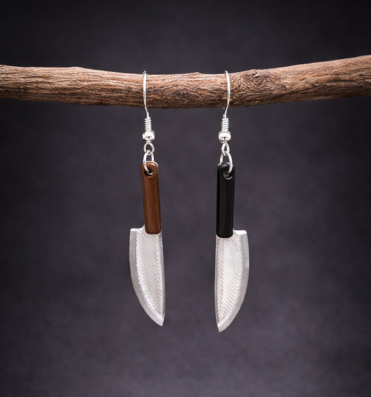 Pair of lightweight knife shaped earrings with silver blade charms and brown and black handles hanging from silver hooks against a dark background
