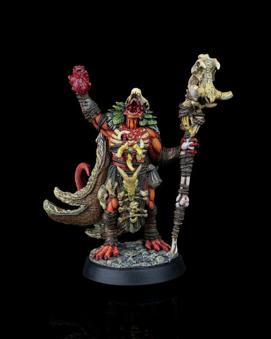 Painted Dragonfolk Shaman miniature with raised heart and tribal staff, posed outdoors