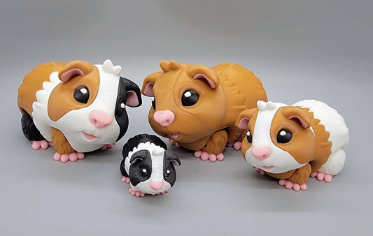 Four articulated guinea pig toys in different sizes and color patterns: tri-color, tan, tan and white, and black and white, displayed on a gray background.
