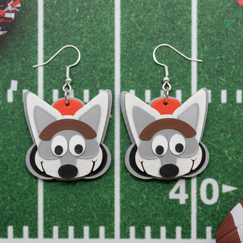 Pair of wolf-shaped earrings with a red hat on a football themed background