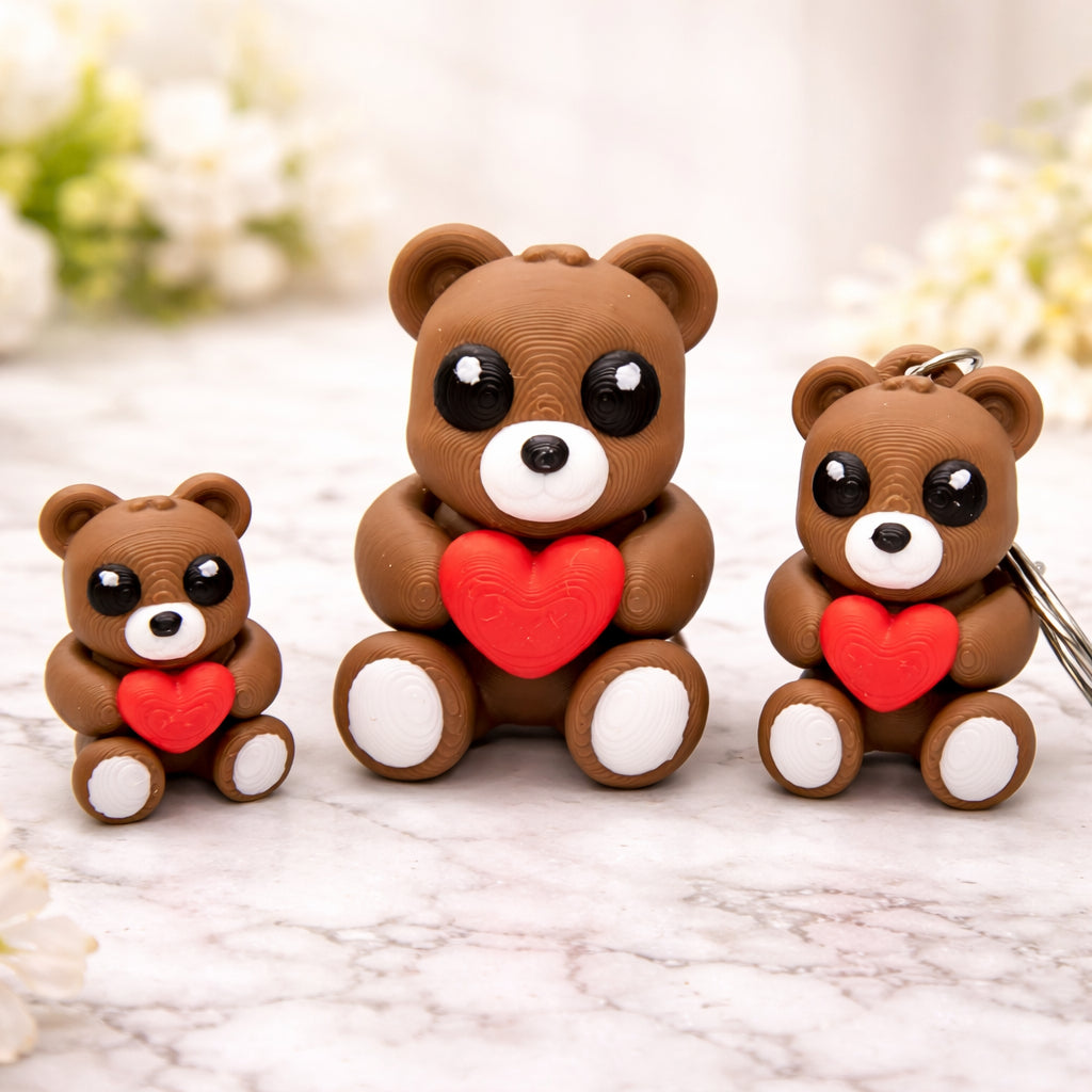 Mini heart teddy bear toys in three sizes, brown cartoon style bears holding red hearts, displayed on a light marble surface with soft floral background, teddy bear toy and keychain options