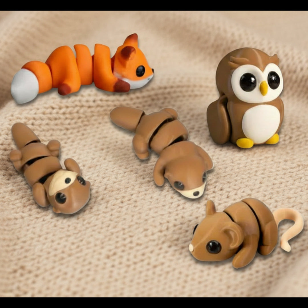 Mini woodland animals fidget toy set featuring articulated 3D printed figures including a fox owl mouse and small critters in warm brown and orange tones displayed on a soft fabric surface designed for sensory play desk decor or gift giving