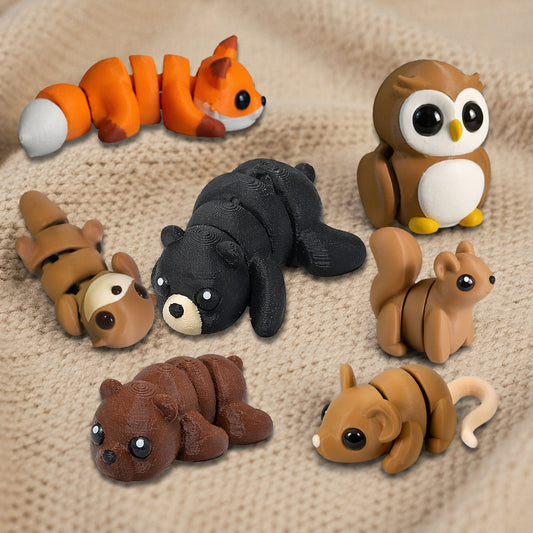 Seven 3D printed articulated woodland animal fidget toys displayed on a knit fabric surface: orange fox, brown owl, black bear, brown bear, mouse, otter, and a squirrel – flexible poseable collectibles by Zou3D