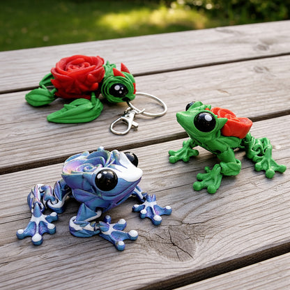 Articulated rose turtle and rose frog toys with flower shell details, shown as colorful 3D printed figures and matching keychain on a wooden surface.