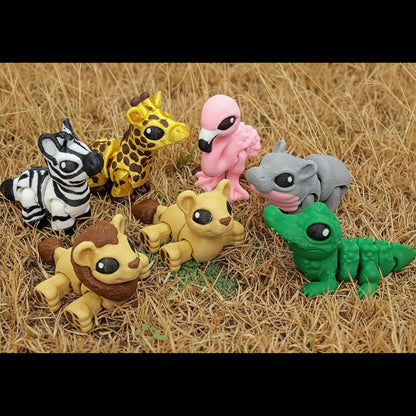 Mini safari animal hatchling toys arranged on dry grass, including a zebra, giraffe, flamingo, lion cubs, crocodile, and hippo in bright, playful colors.