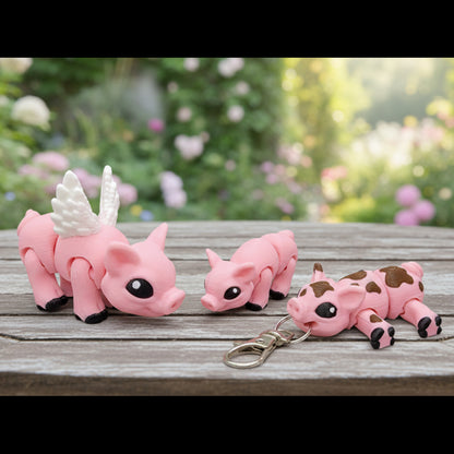 Small pink pig figurines on a wooden surface, including a winged pig figure, a pig keychain, and a pig magnet