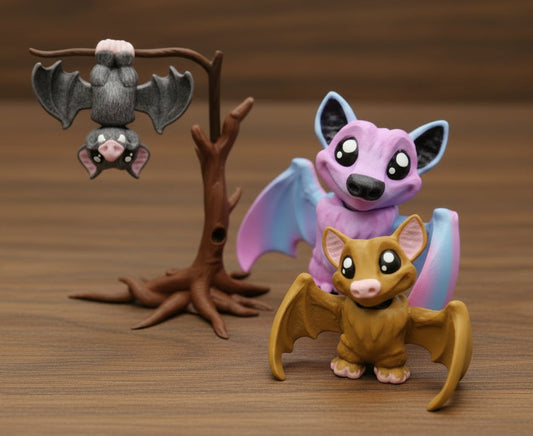 Three mini bats, one hanging on a brown tree, sitting on a desk