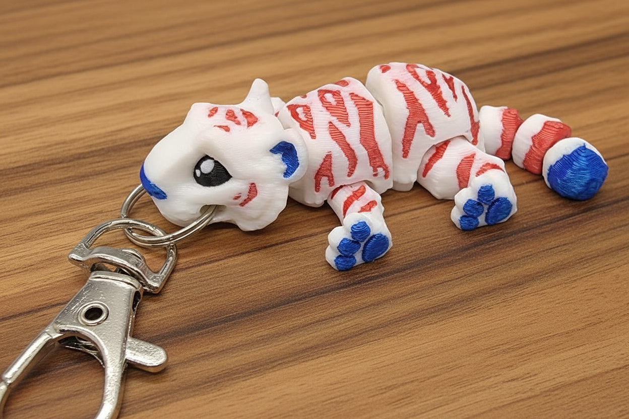 red white and blue mini tiger toy keychain on a wooden surface