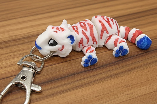 red white and blue mini tiger toy keychain on a wooden surface