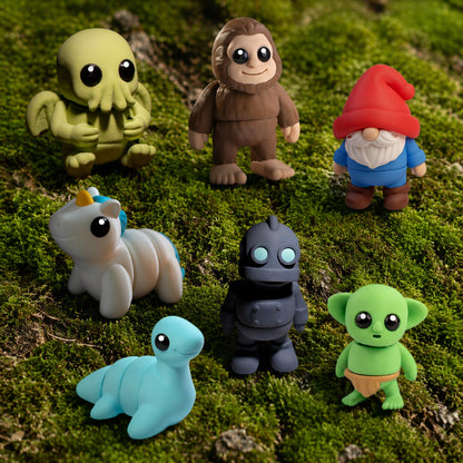7 Mini Mythical Pals 3D printed articulated fidgets posed on green moss — Cthulhu, Bigfoot, Gnome, Unicorn, Iron Giant, Nessie, and Goblin by Zou3D