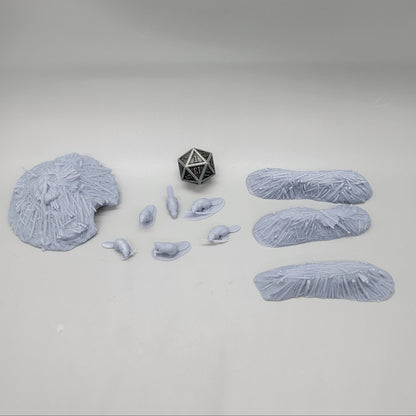 Top-down view of the unpainted resin Beaver Pack scatter set featuring 6 beaver miniatures, 3 dams, 1 lodge, and a D20 die for scale.