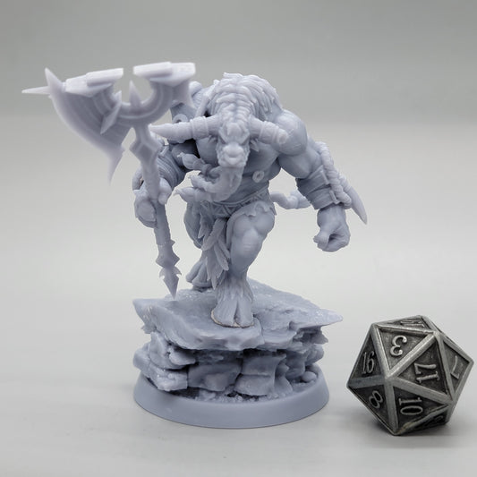 Unpainted 32mm minotaur holding a large axe over its shoulder on a layered rocky base beside a metal d20.