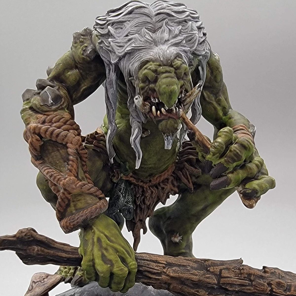 Painted Hag Cursed Troll 2 gripping a wooden club above a fallen log on a decorated scenic base.