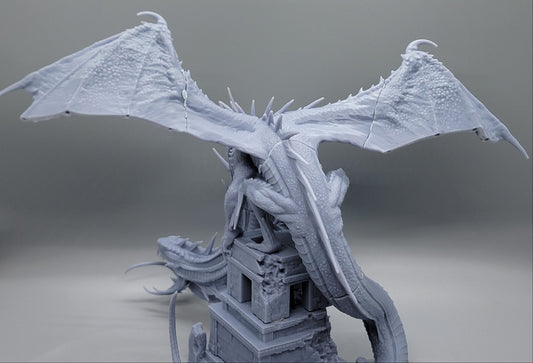 Rear view of Heavenly Ophidian resin dragon with outstretched wings, and ruined stone tower base.