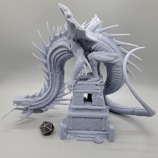Heavenly Ophidian Gargantuan snake dragon resin miniature test fitted on a ruined stone tower with a D20 die for scale.
