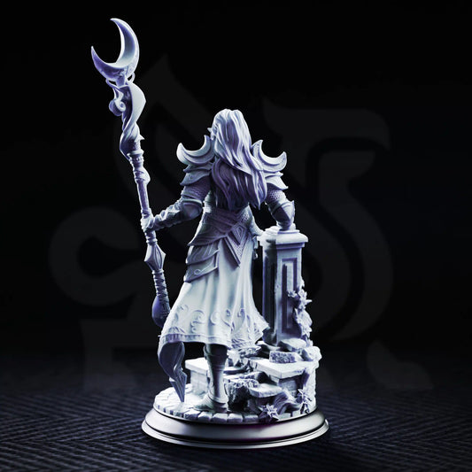 Rear view of Kadna Glydrin Drow sorcerer miniature showing long hair, crescent shoulder armor, engraved robes, staff, and ruined base