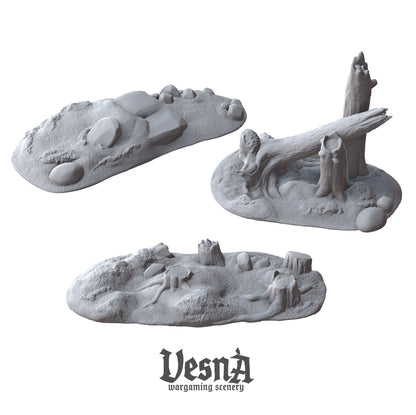 Isometric view of three unique unpainted gray resin forest scatter terrain mounds by VESNA Sculpts, showing a rocky hill, a tree stump patch, and a large leaning fallen log.