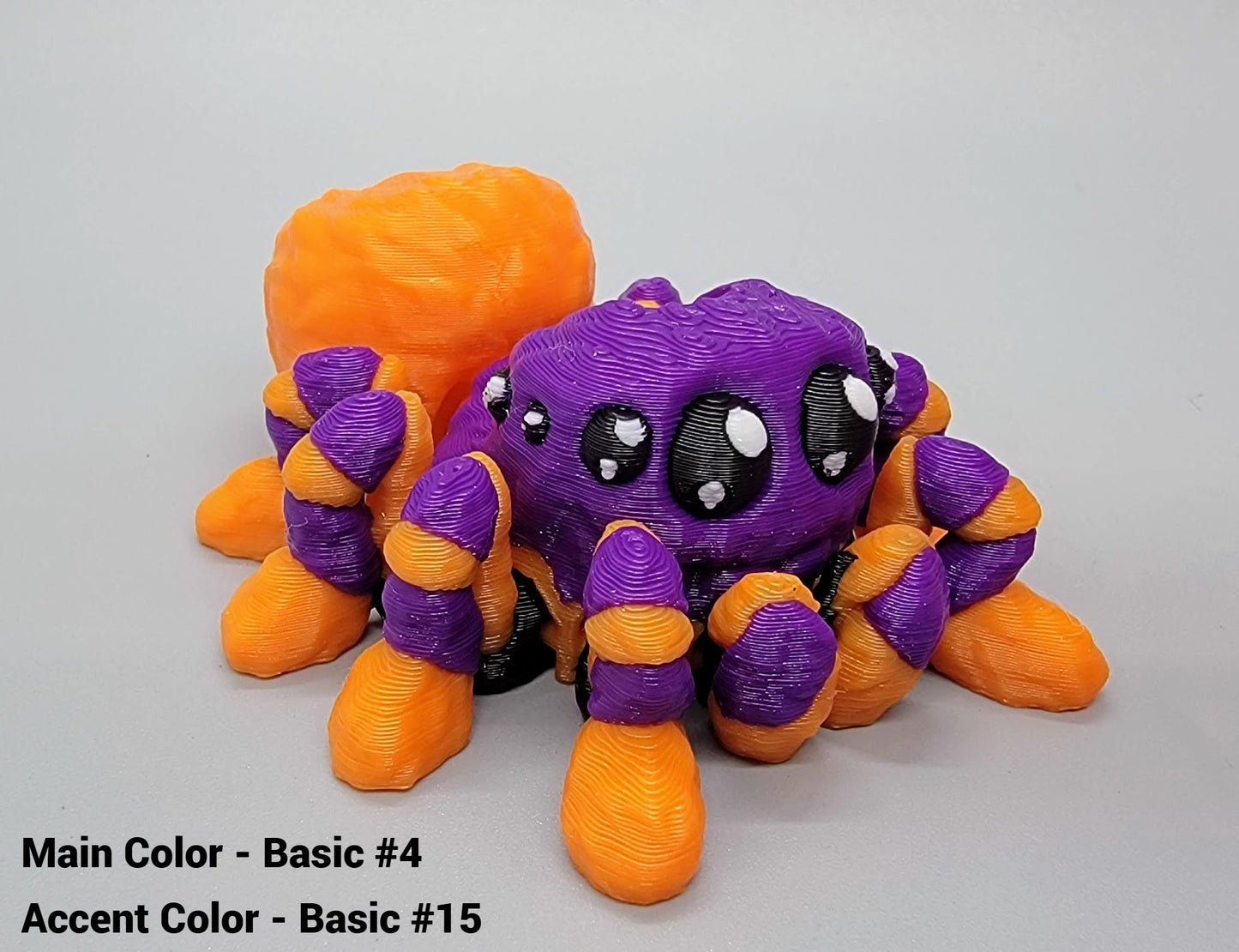 3D-printed spider toy with purple and orange colors on a gray background