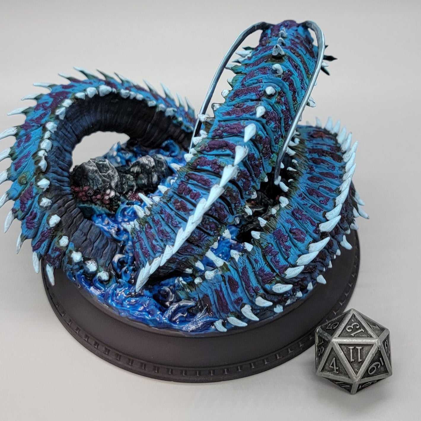 Side view of painted Old Mawgrin sea serpent miniature with barnacles, fins, and ocean base details