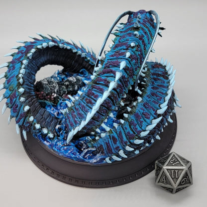 Side view of painted Old Mawgrin sea serpent miniature with barnacles, fins, and ocean base details