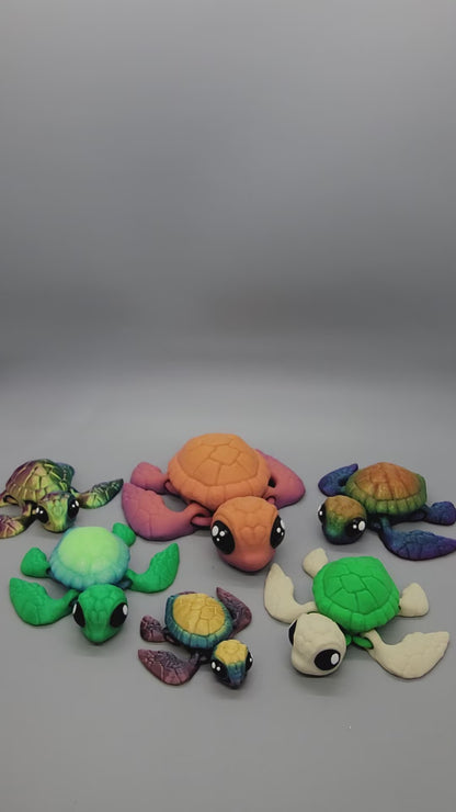 Showcase of small turtle keychains with cartoon eyes in various mixes of colors including green, yellow, blue, orange, and pink, along with 1 rainbow turtle.