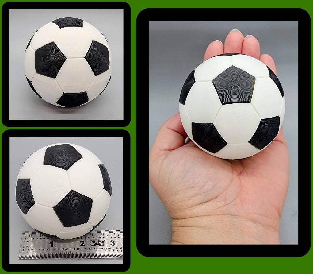 Black and white soccer clicker ball shown held in hand and measured with ruler for scale