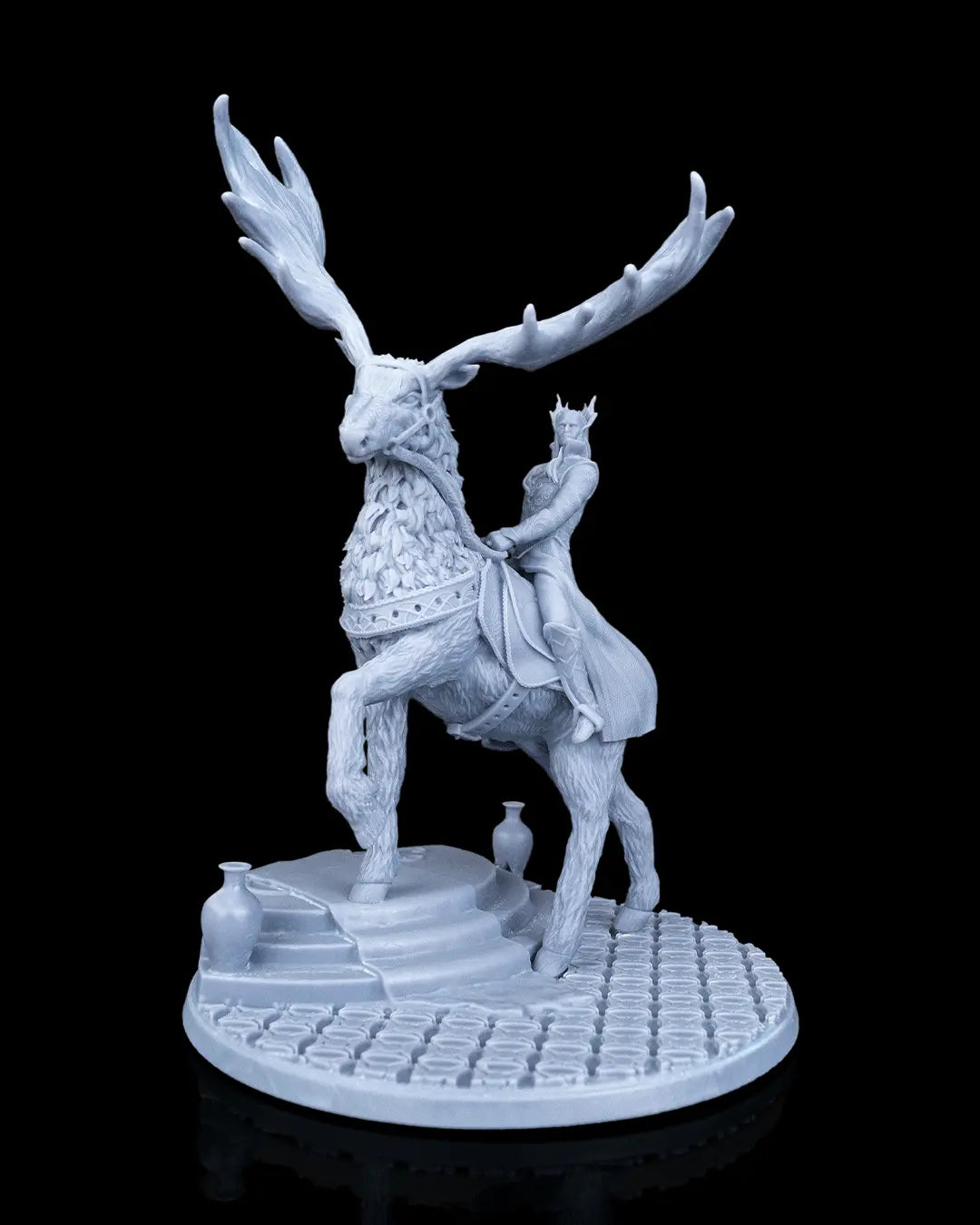 Front view of the unpainted resin miniature Tharion and Vaelor showing an Elven king with a crown riding a giant elk on a scenic paved base.