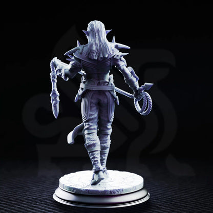 Rear view of Vessels of Irinax Drow Soldier 3 showing long hair, spiked armor, a bladed whip, layered clothing, and stone base