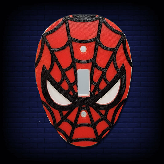 Webbed-Man themed light switch cover on a dark blue brick wall background