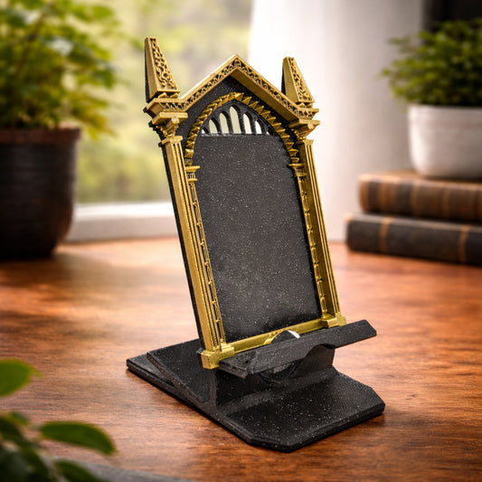 Custom 3D printed wizard themed gothic phone stand on a desk next to books. Shown in Bronze frame and Sparkle Black mirror colors.